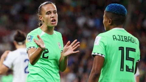 Two Nigeria players gesture at each other in frustration during their World Cup game against England