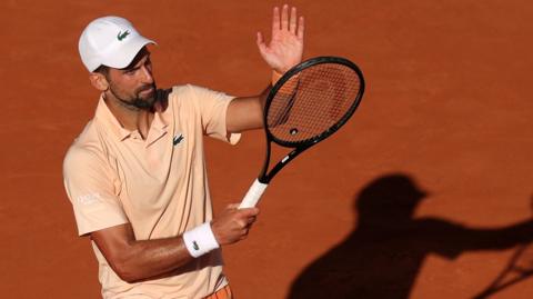 Novak Djokovic applauds using his racquet