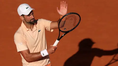 Novak Djokovic applauds using his racquet
