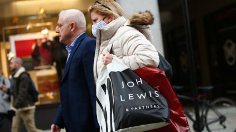 Woman carrying John Lewis shopping bag.