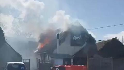 Fire and smoke on the roof of an Indian restaurant in daylight