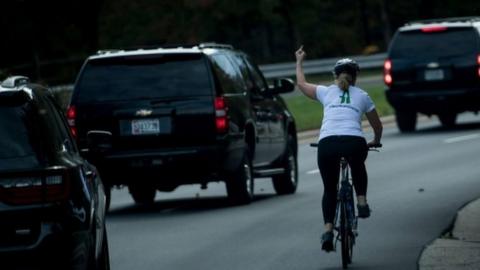 Ms Briskman cycling past the motorcade, making an obscene gesture.