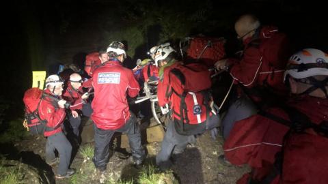 A man is carried down the mountain on a stretcher