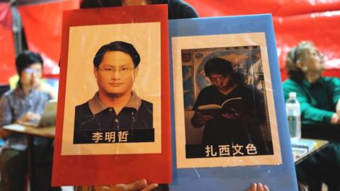 A volunteer holds placards of detained Taiwanese activist Lee Ming-cheh and Tibetan education advocate Tashi Wangchuk in Taipei on June 4, 2017