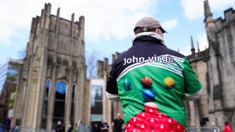A man wearing a shirt with a snooker table and balls printed on stood outside Sheffield Cathedral.