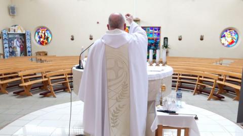 A priest celebrating Mass in an empty church during the first lockdown