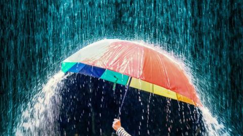 Cropped Hand Holding Umbrella During Rainfall - stock photo