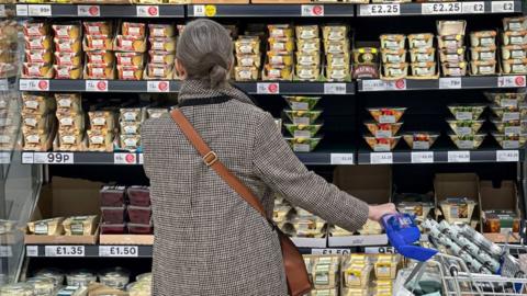 Woman looking at supermarket shelves