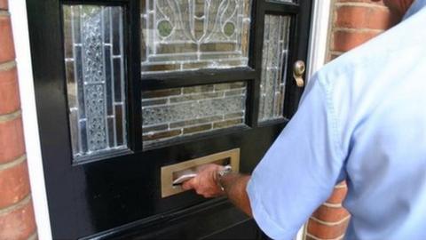 Postman putting letters through a letter box