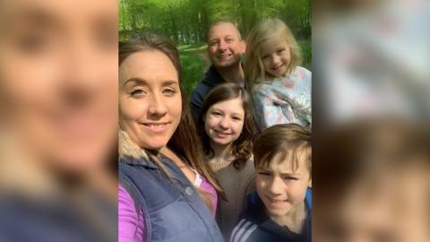 Mark Hillier in a selfie with his wife Holly and three children, stood amongst trees