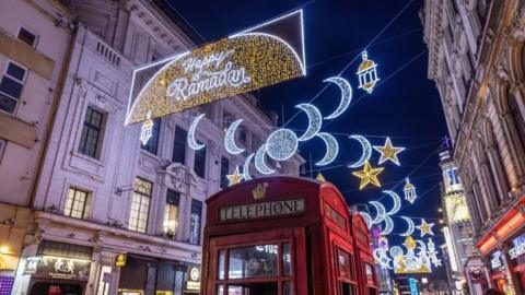 Red telephone box in the foreground of Ramadan lights in Piccadilly