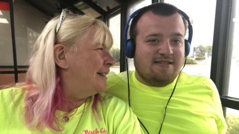 Woman with long blond hair and young man with short brown hair wearing headphones