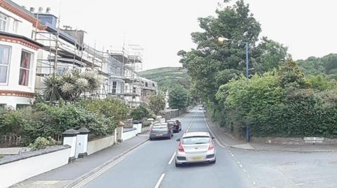 Cars parked at the side of the road with another overtaking