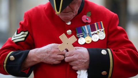 A Chelsea Pensioner holds a cross