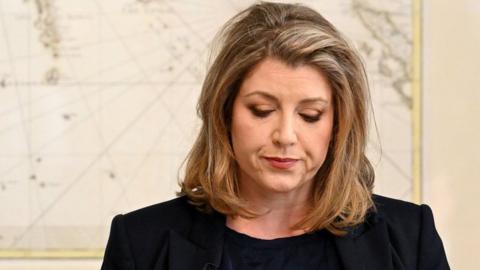 Penny Mordaunt stood at event next to map