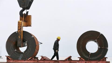 This photo taken on May 19, 2018 shows a worker preparing to lift a roll of steel with a crane at a shipyard in Nantong in China's eastern Jiangsu province.