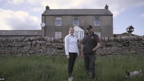 A couple, Sarah and Neil Robson standing outside their remote farmhouse