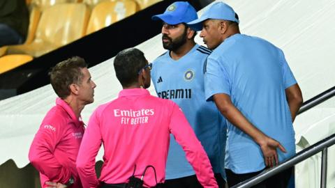 Umpires (L) talk with India's captain Rohit Sharma (2R) and coach Rahul Dravid (R) after rain stopped play during the Asia Cup 2023 super four one-day international (ODI) cricket match between India and Pakistan at the R. Premadasa Stadium in Colombo