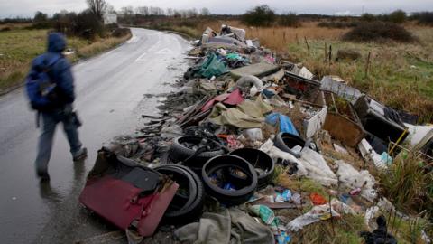 A huge pile of rubbish dumped at the side of a country lane