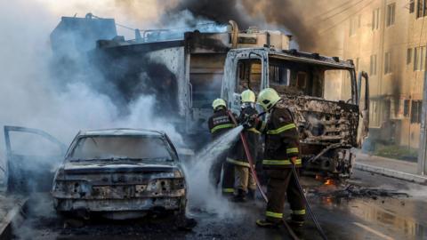 This picture released by O Povo shows firefighters putting out a burning truck and car during a wave of gang violence in Brazil