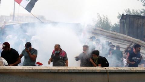 Demonstrators cover their faces from tear gas during a protest in Baghdad on 25 October 2019