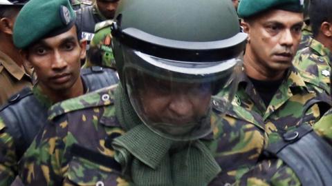 sacked oil minister Arjuna Ranatunga (C) is escorted to safety