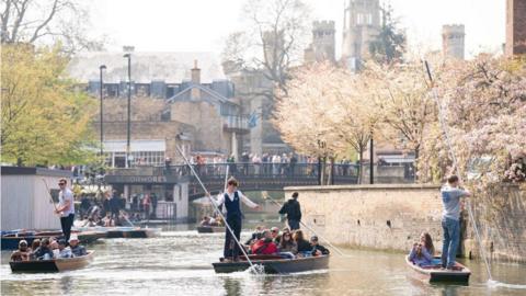 People punting and walking along a bridge in Cambridge