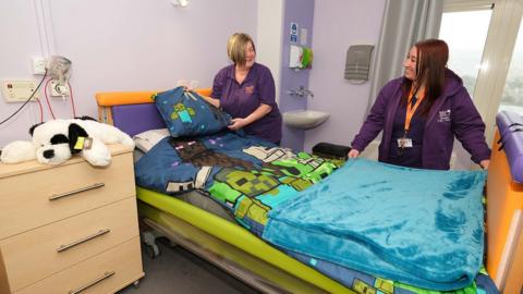 Two care workers making a bed in a room at Bluebell Wood Children's Hospice