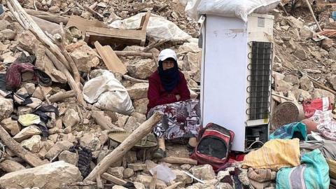 A woman sits among rubble after a powerful earthquake struck the Moroccan village of Douzrou