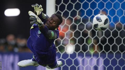 Francis Uzoho hangs almost horizontally in the air as he dives in vain to save a ball that is passing him into the net