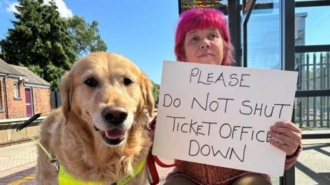 Sarah Leadbetter holding a 'Please do not shut ticket offices down' sign alongside her guide dog, Nellie