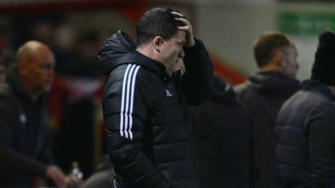 Exeter City manager Gary Caldwell holding his head