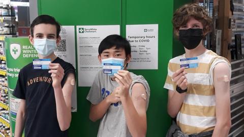 Jack, Wesley and Darcy pose with their Covid vaccination cards