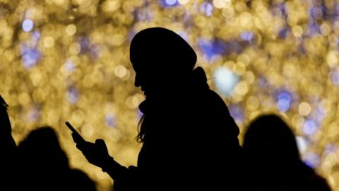 A woman holds a phone near Christmas and New Year light installation in Moscow, Russia December 17, 2018