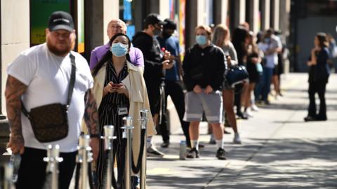 People queue outside a shop in London