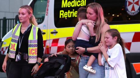 A woman and her children walk away from the Bondi Junction mall