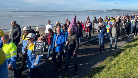 Protestwyr yn cerdded ar hyd traeth Aberafan, Port Talbot