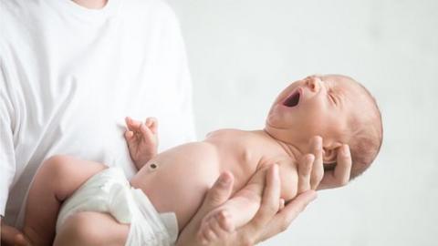 A newborn held by a man