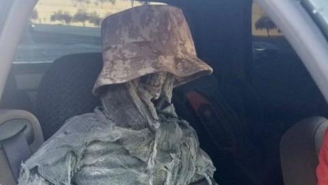 A fake skeleton in a camouflage bucket hat sits in the front of a vehicle in a handout image by the Arizona Department of Public Safety