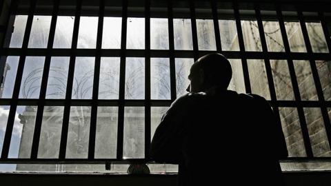 An inmate at a Young Offenders Institution looking out of the window