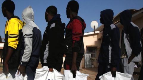 Gambian migrants who returned voluntarily from Libya stand in line with plastic bag from the International Organization for Migration (IOM) as they wait for registration at the airport in Banjul, Gambia April 4, 2017