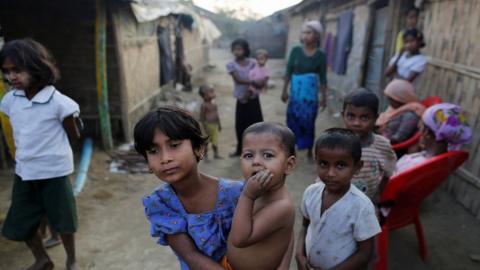 A Rohingya refugee girl carries a baby inside a refugee camp in Sitwe, in the state of Rakhine, March 2017