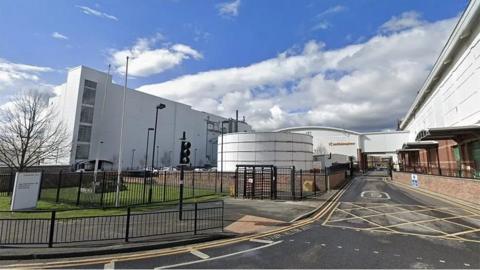 The exterior of the Hull plant, which has large grey buildings secured by a black metal fence.