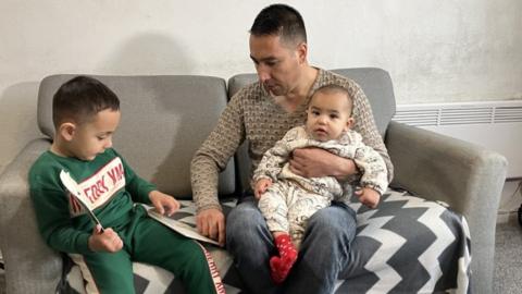 Sayed Sadat with his family in their rented Sheffield home