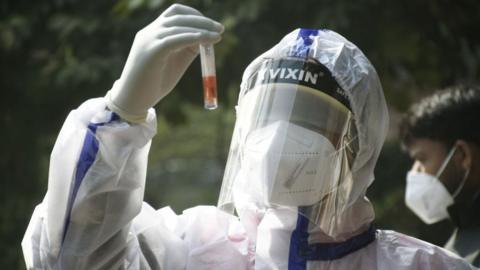 A health worker holds a Covid-19 test sample after people were being tested in Nehru Nagar, A block, after two people allegedly tested positive for the Omicron variant, on December 18, 2021 in Ghaziabad, India.