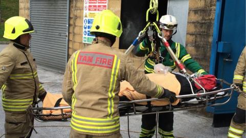 A crane is used to bring a mannequin out of a first storey bedroom in a fire rescue training exercise near Cardiff
