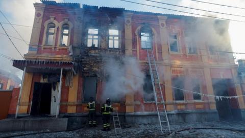 Firefighters work outside an office building destroyed in shelling in Donetsk