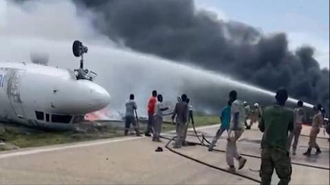 Firefighters in Somalia putting out fire by crash-landed plane