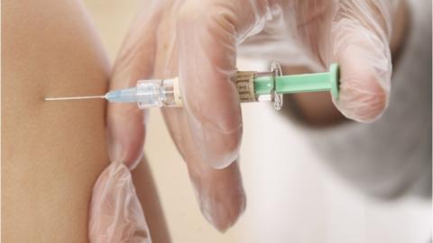 A needle being injected into a girl's arm