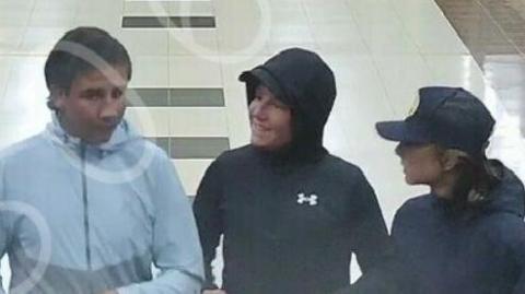 A grainy CCTV still of three boys walking through a shopping centre. They are wearing hooded coats and talking to each other.